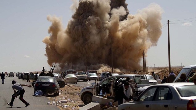 Rebeldes fogem durante ataque aéreo das forças do governo de Muamar Kadafi na região petrolífera de Ras Lanuf, Líbia. Manifestações violentas contra o governo de 42 anos do ditador marcaram a Primavera Árabe