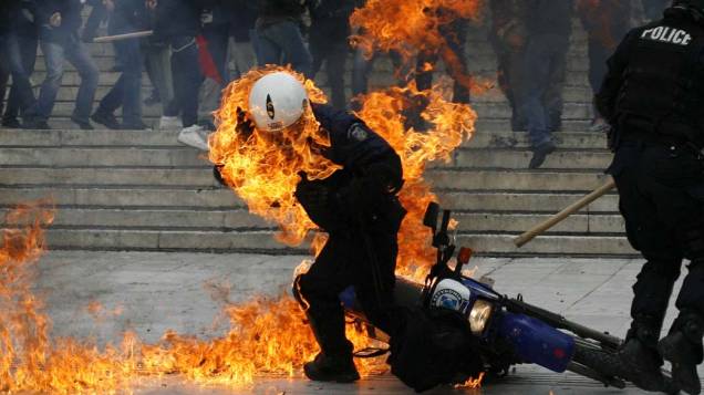Policial atingindo por um coquetel molotov durante greve dos funcionários públicos em Atenas, na Grécia