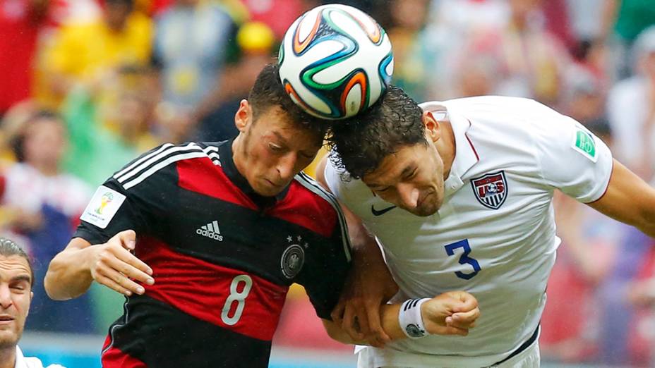 O alemão Ozil disputa de cabeça a bola com o americano Omar Gonzalez na Arena Pernambuco, em Recife