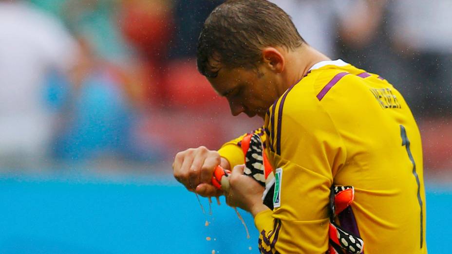 O goleiro da Alemanha, Manuel Neuer, torce luva encharcada após o primeiro tempo da partida contra os Estados Unidos, na arena Pernambuco, em Recife