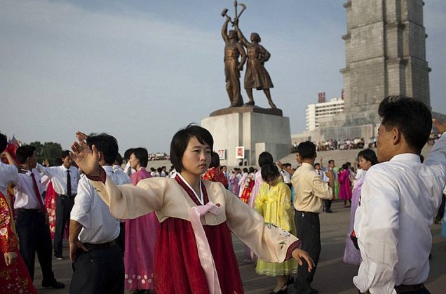 Jovens dançam em frente a torre Juche em Pyongyang