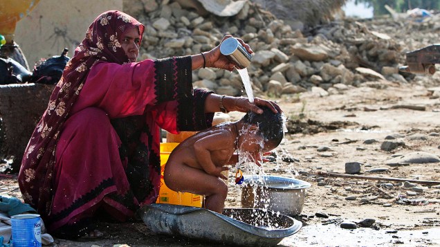  Nesta quinta-feira (27) mulher dá banho em filho em meio a destroços de sua casa, destruída pelo terremoto de magnitude 7,7 que atingiu a região do Baluchistão (Paquistão) na terça-feira (24)
