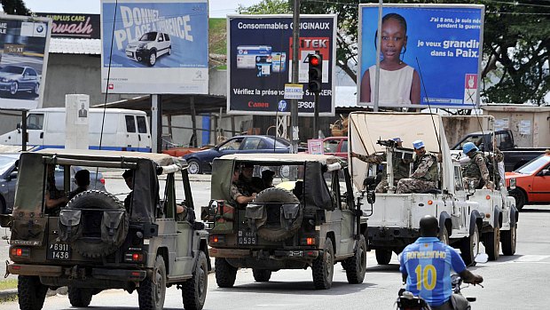 Tropas da missão de paz das Nações Unidas passam por motociclista com a camisa de Ronaldinho, nas ruas de Abidjan, sede do governo da Costa do Marfim