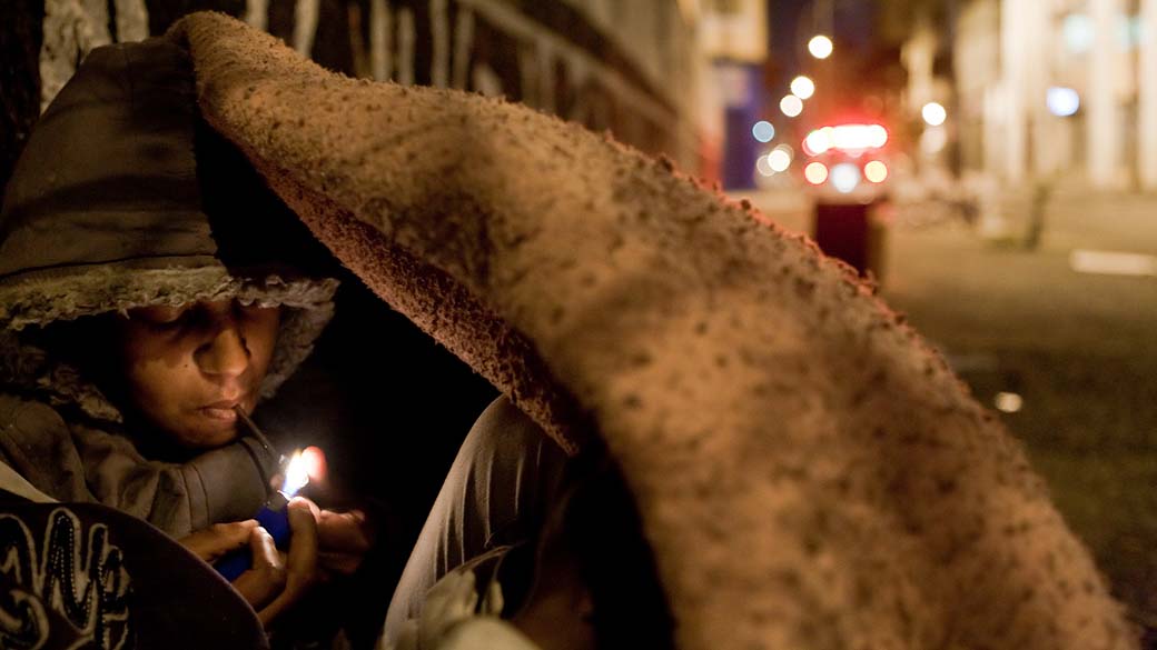 Jovem de 16 anos acende cachimbo de crack, na rua dos Gusmões, região da nova cracolândia, no centro de São Paulo