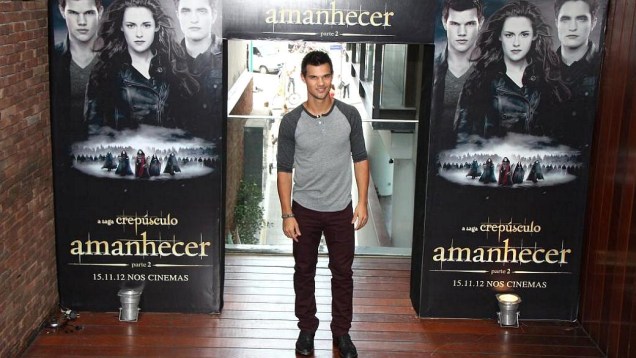 Crepúsculo: Taylor Lautner posa para foto em frente ao cartaz do quinto e último filme da saga, Amanhecer - Parte 2