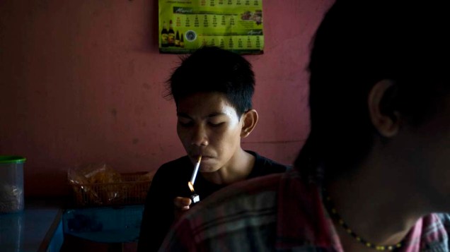 Estudante fuma antes da escola na cidade de Yogyakarta , Indonésia