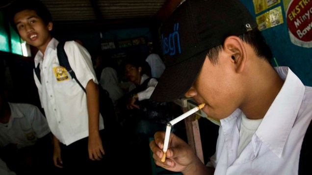 Estudantes fumam antes de ir para a escola em Yogyakarta, Indonésia. A população mais pobre da Indonésia chega a gastar 20% de seu salário em cigarros