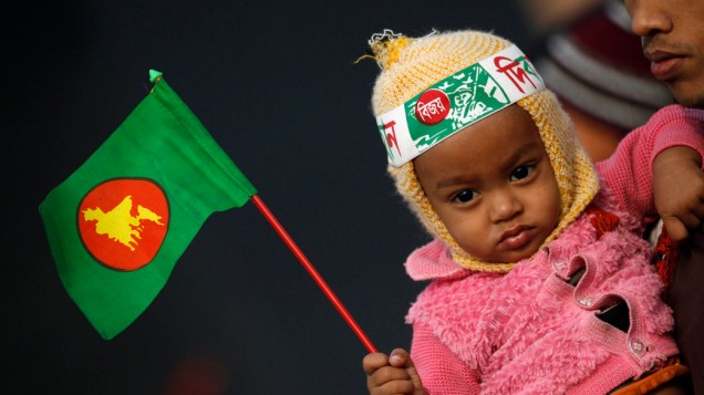 Garota com a bandeira de Bangladesh durante visita ao memorial de mártires da guerra de independência do país de 1971