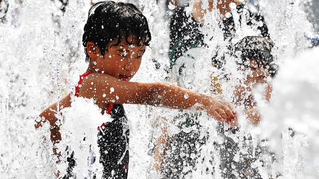 Menino brinca em uma fonte, em Seul. Meteorologistas preveem forte calor para a capital sul-coreana