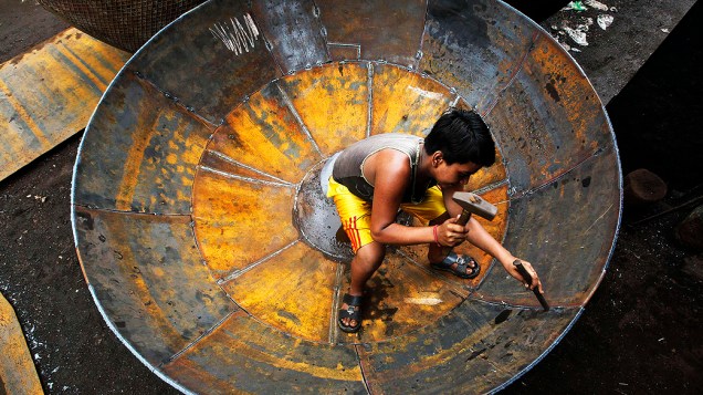 Garoto dentro de um gigante utensílio de ferro em Kolkata, na Índia
