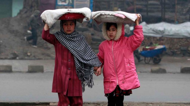 No Afeganistão, meninas carregam pão em uma rua de Cabul