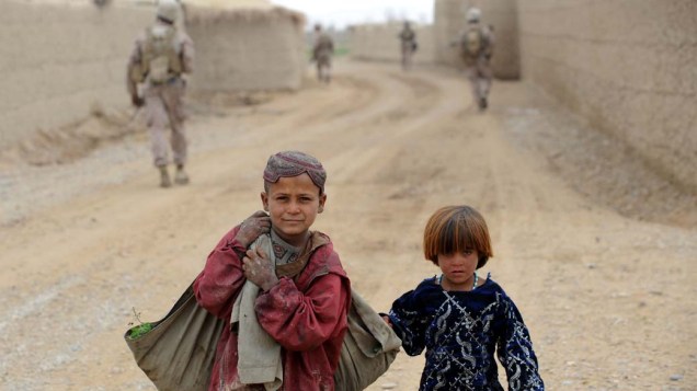 Crianças afegãs caminham nas proximidades do 2° Batalhão da Marinha Americana, na província de Helmand