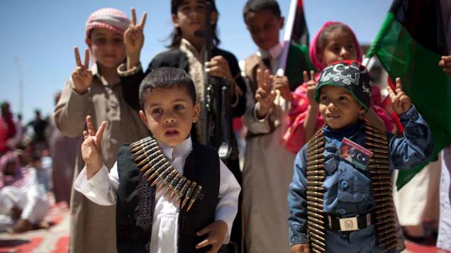 Em Ajdabiya, crianças líbias posam para foto com cintos de munição<br>  