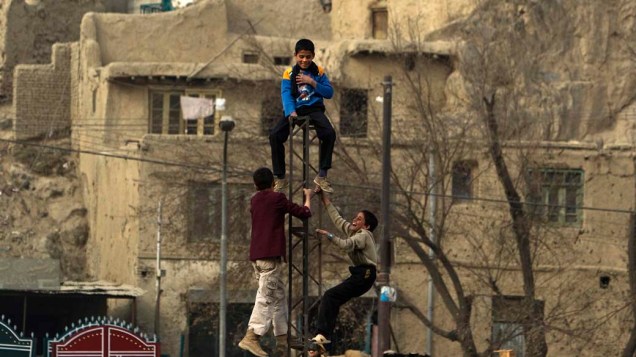 Crianças afegãs brincam em poste elétrico quebrado em Cabul