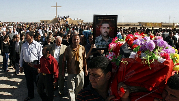 Cristãos iraquianos carregam os caixões de seus parentes mortos