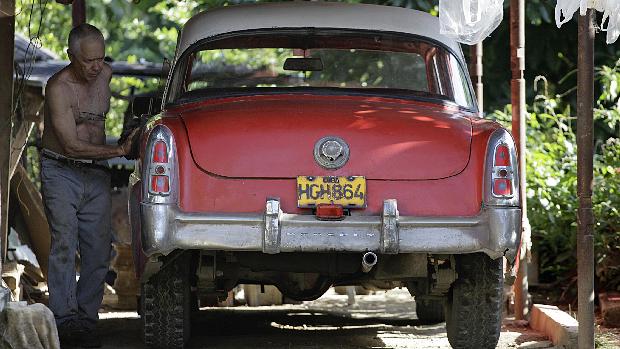 Cubano cuida de carro, um modelo de 1952, em sua casa, em Havana