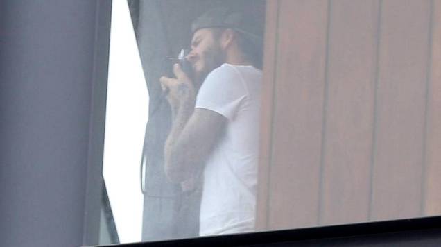 David Beckham aparece na sacada do hotel onde está hospedado, no Rio