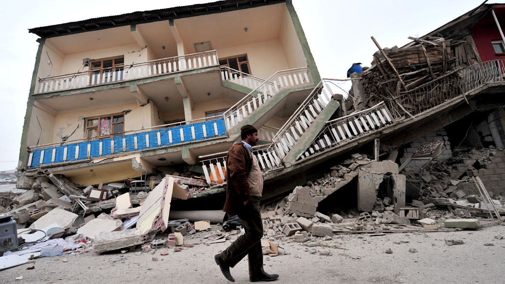 Turco passa por residência abalada após o terremoto em Ercis, Turquia