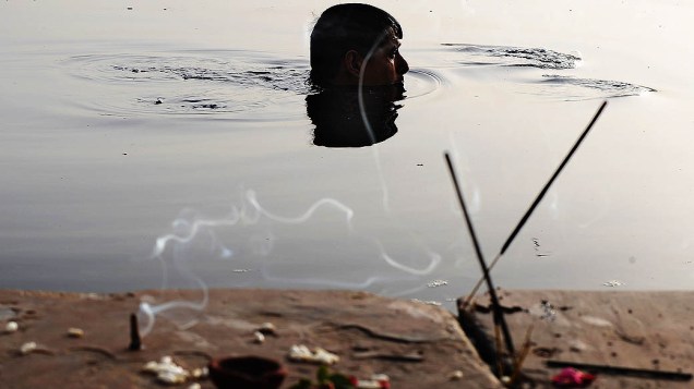 Devoto hindu mergulha no rio Yamuna, em Nova Déli, na Índia, após apresentar oferendas ao Sol e ao Rio para marcar o inínio da celebração Nirjala Ekadashi