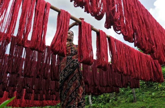 Mulher pendura fios tingidos para secar em tecelagem na cidade de Agartala, na Índia. A região concentra as maiores produções têxteis do país, impulsionando a economia local.