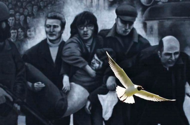 Uma gaivota voa em frente à pintura em Londonderry, na Irlanda do Norte. A figura retrata Jackie Duddy sendo carregado por homens e um padre católico em 1972, no dia conhecido como Bloody Sunday.