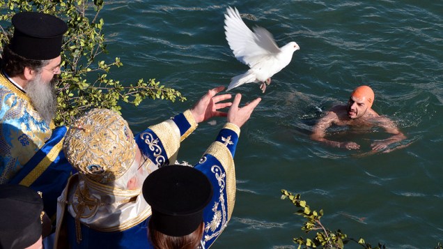 Padre solta pomba durante a bênção das águas que marcam as celebrações da Epifania na cidade de Volos, na Grécia
