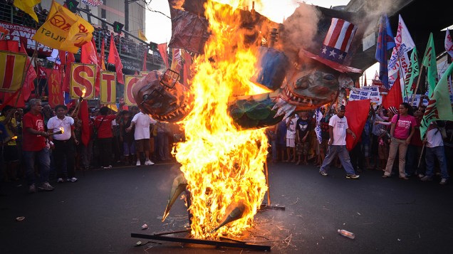 Manifestantes colocam fogo em uma efígie do presidente filipino Benigno Aquino e do presidente dos Estados Unidos, Barack Obama, durante protesto em Manila