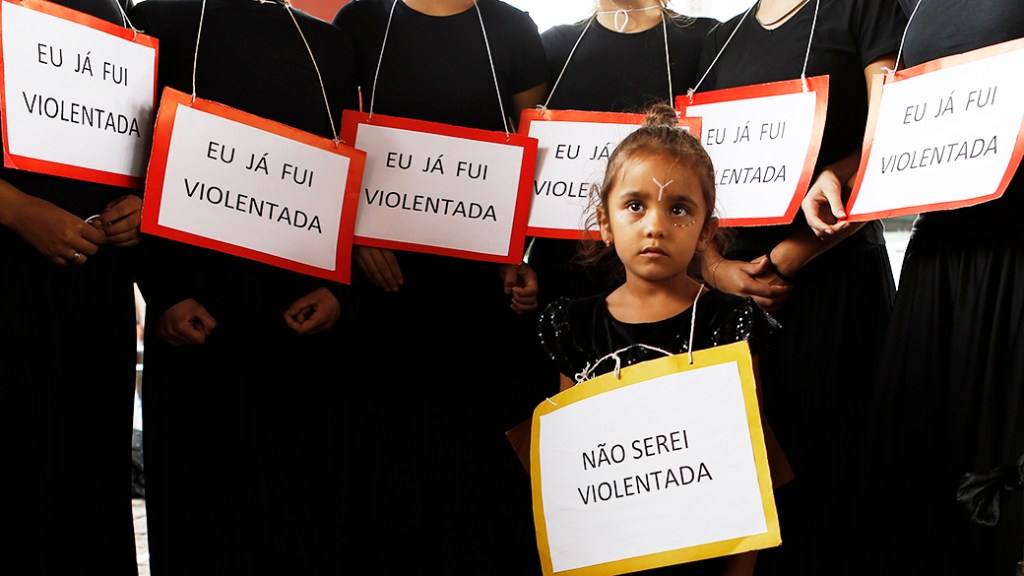 Menina segura um cartaz sobre a violência praticada contra as mulheres durante marcha para marcar o Dia Internacional da Mulher, em São Paulo
