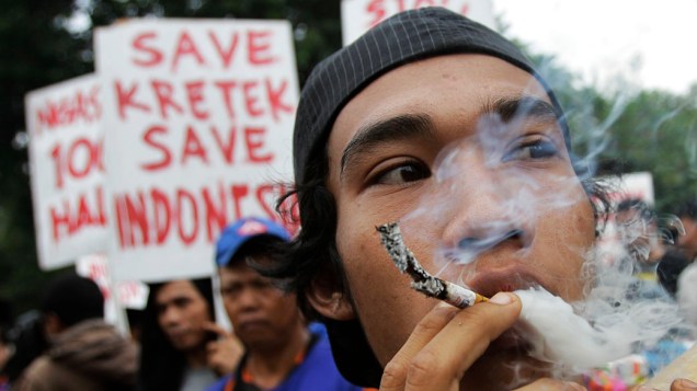 Vendedor de cigarros fuma como protesto durante comício contra o Dia Mundial Sem Tabaco, em Jacarta, Indonésia
