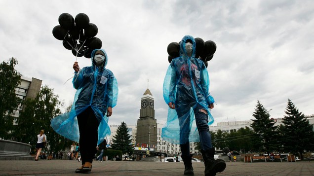 Jovens ativistas, usam máscaras e seguram balões pretos, para participar de um flash mob contra o tabagismo durante o Dia Mundial Sem Tabaco no centro de Krasnoyarsk, Rússia