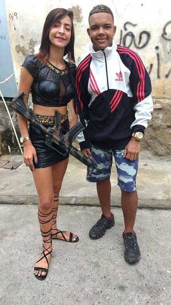 Outra jovem se exibe armada com um fuzil a tiracolo