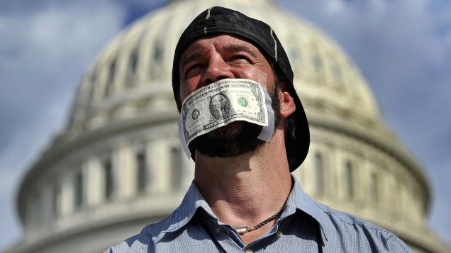Americano cobre a boca com nota de um dólar durante um protesto contra a paralisação dos serviços do governo federal, em frente ao Capitólio, em Washington