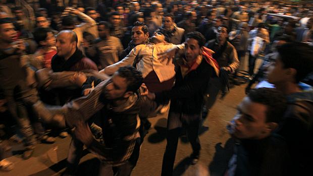 Egípcios carregam manifestante ferido por gás lacrimogênio durante confronto no Cairo