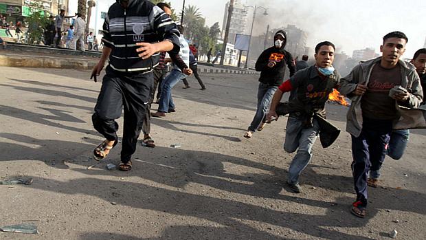 Manifestantes correm da polícia em protesto em Suez, em 27 de janeiro de 2011
