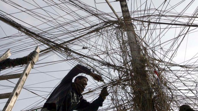 Eletricista revisa cabos de energia no bairro de Karrada, Bagdá