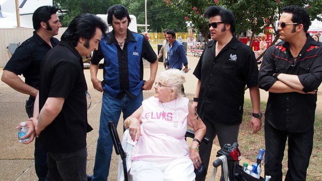 Sósias de Elvis Presley em volta de uma fã do cantor em Gracelando durante a Elvis Week