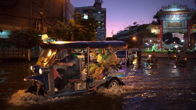 Motorista de Tuk Tuk dirige por ruas alagadas de Bangcoc, na Tailândia