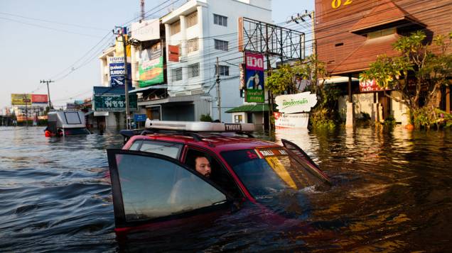 Homem empurra seu carro em rua alagada em Bangcoc, Tailândia