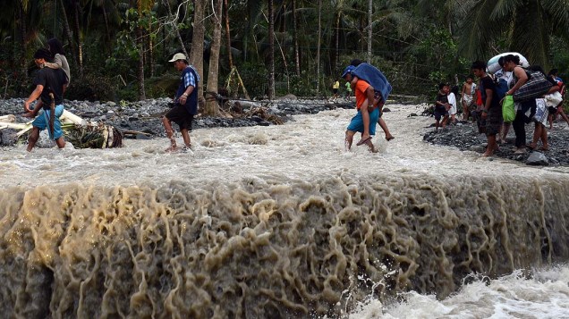 Moradores atravessam estrada destruída pelo tufão Bopha, na aldeia de Andap, Filipinas