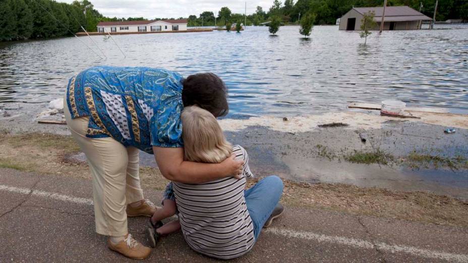 Família observa sua casa tomada pela enchente em Vicksburg, nos Estados Unidos
