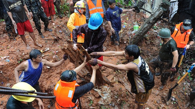 Equipe de resgate e voluntários vasculham os escombros em busca de sobreviventes no local onde quatro casas desabaram em Quezon, ao norte de Manila
