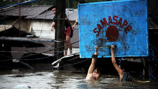 Moradores tentam se salvar em rua alagada na região metropolitana de Manila. Cinco morreram e sete estão desaparecidos por conta das chuvas. Desde o início das tempestades no país, 53 pessoas morreram