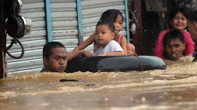 Moradores tentam sair de rua alagada na região metropolitana de Manila, nas Filipinas