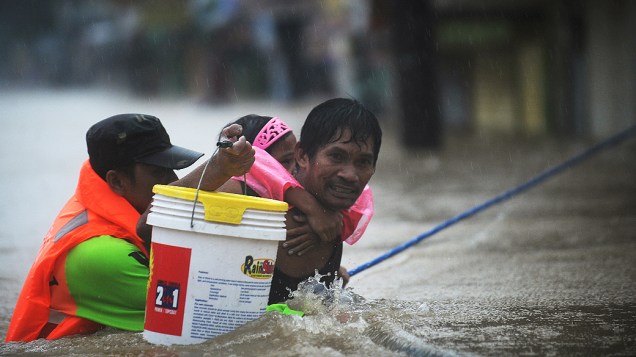 Moradores são resgatados em rua alagada na região metropolitana de Manila. Cinco morreram e sete estão desaparecidos por conta das chuvas. Desde o início das tempestades no país, 53 pessoas morreram