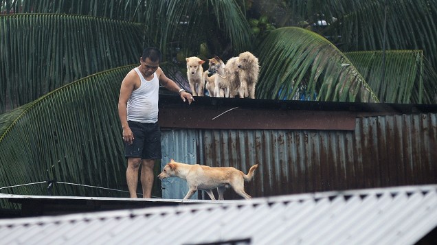 Homem pede ajuda em cima de sua casa na região metropolitana de Manila, nas Filipinas