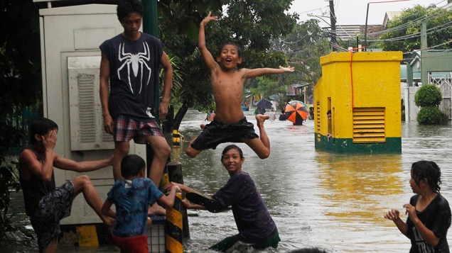 Crianças brincam em rua alagada de Las Pinas, nas proximidades de Manila