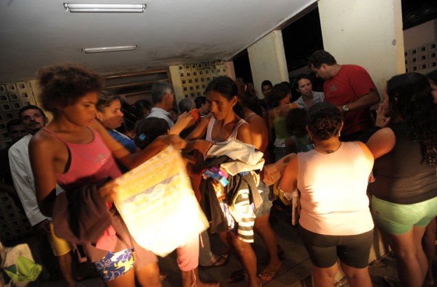 Pessoas alojadas em uma escola estadual da região recebem donativos.