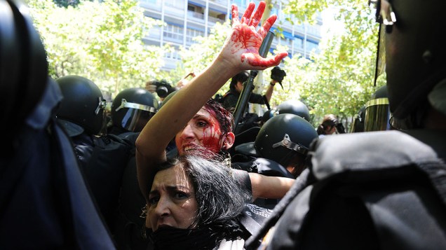 Mulher suja de sangue é cercada por policiais durante conflito entre as forças de segurança espanholas e mineiros em Madri. Os trabalhadores protestam contra cortes de subsídios à produção de carvão