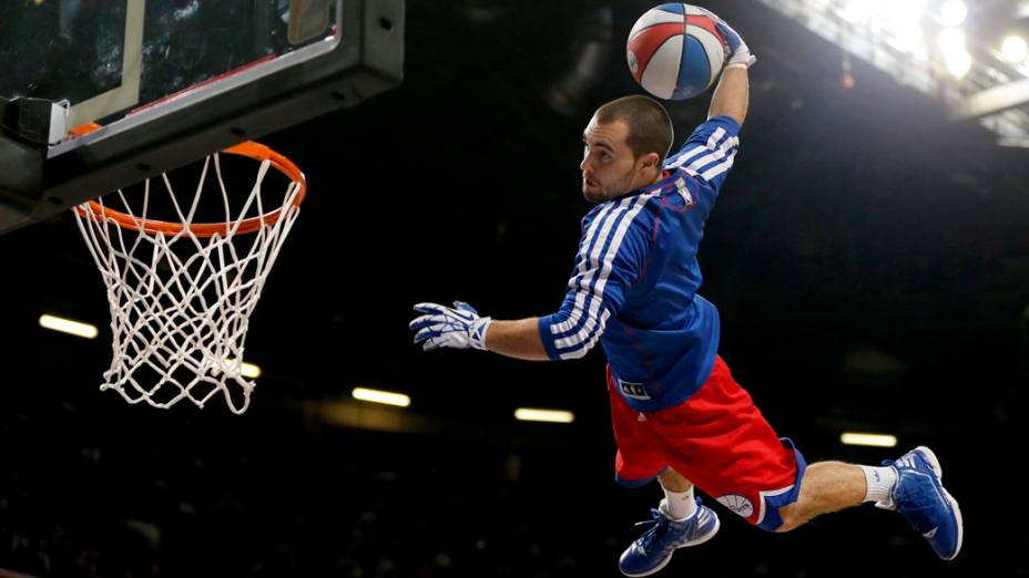 Jogador de uma equipe de acrobacias, usa cama elástica para dar uma enterrada durante exibição antes da partida entre o Oklahoma City Thunder e Philadelphia 76ers em Manchester, na Inglaterra