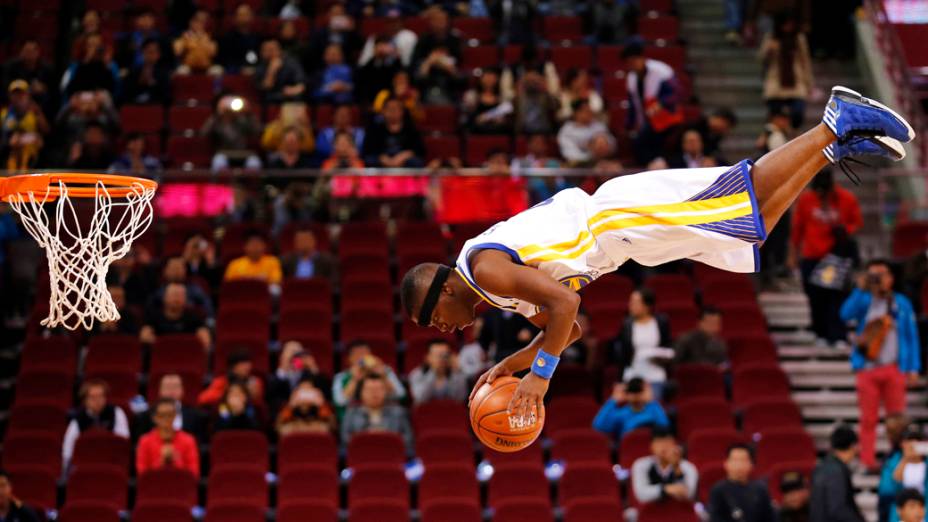 Jogador da equipe de acrobacias do Golden State Warriors, usa cama elástica para dar uma enterrada durante exibição antes da partida contra o Los Angeles Lakers em Pequim, na China